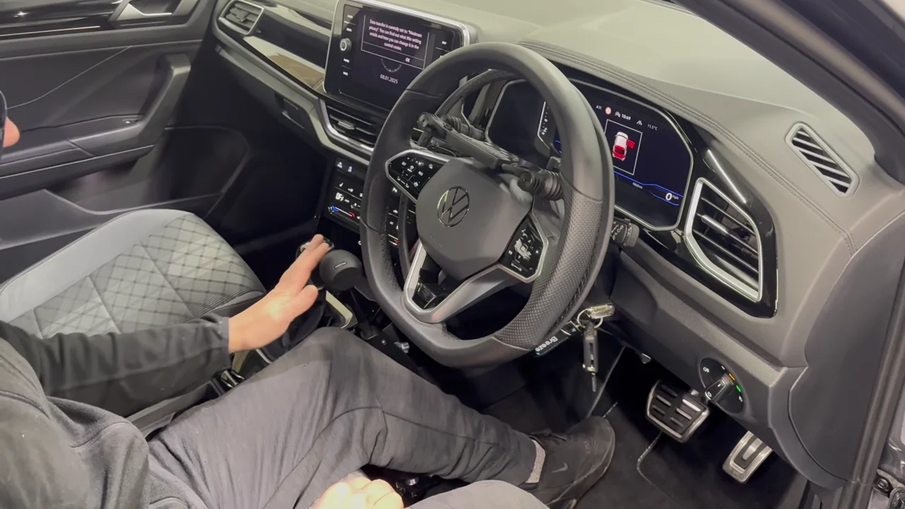 A driver demonstrating the steering aid and hand controls fitted to a car